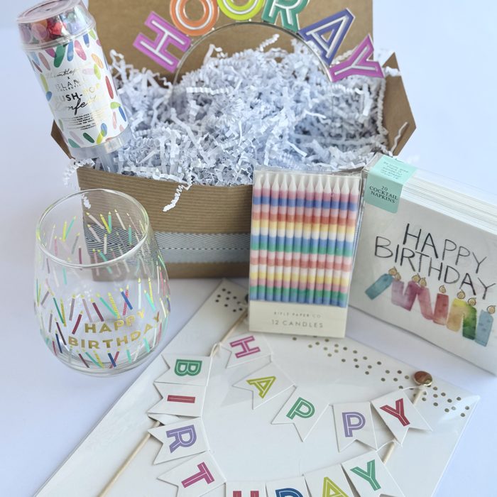 Colorful birthday gift basket with a Hooray headband, candles, and a wine glass